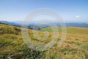 Iew of the mountains in the Ukrainian Carpathians, green grass and mountains in blue haze, Mountain meadow and blue sky,