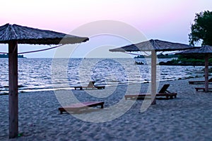 Iew of sandy beach with bamboo umbrellas and sun beds at sunrise