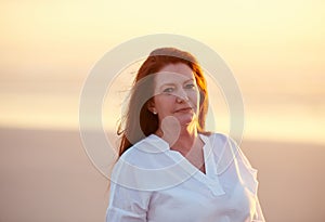 If anybody needs me, Ill be at the beach. mature woman standing on the beach at sunset.