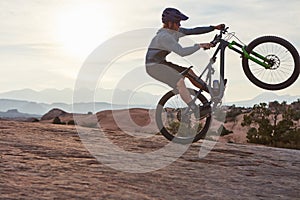 If its not risky, what the fun. a young man out mountain biking during the day.