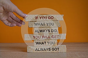 If you do what you always did, you will get what you always got. Red words on brick blocks. Beautiful wooden table orange