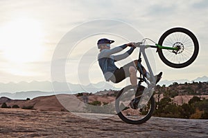 If youre not taking risks, youre not really living. a young man out mountain biking during the day.