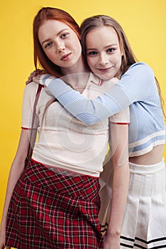 ifestyle people concept: two pretty young school teenage girls having fun happy smiling on yellow background