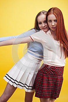 ifestyle people concept: two pretty young school teenage girls having fun happy smiling on yellow background