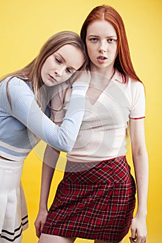 ifestyle people concept: two pretty young school teenage girls having fun happy smiling on yellow background