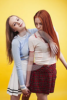 ifestyle people concept: two pretty young school teenage girls having fun happy smiling on yellow background