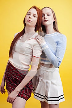 ifestyle people concept: two pretty young school teenage girls having fun happy smiling on yellow background