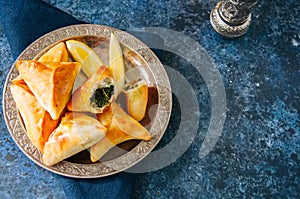 Iftar food during ramadan, arabic and middle eastern food concept. Fatayer sabanekh - traditional arabic spinach triangle hand pi