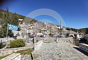 Igiades village on the mountain mitsikeli, greek fllag waving old traditional houses in ioannina