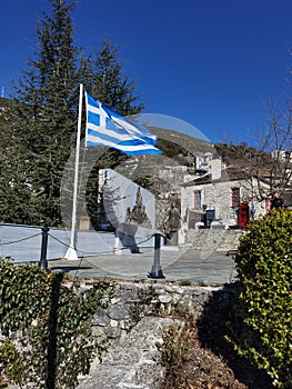 Igiades village on the mountain mitsikeli, greek fllag waving old traditional houses in ioannina