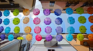 Iglesias, Italy: Colorful umbrellas hanging over a street in old Iglesias city in a sunny day photo