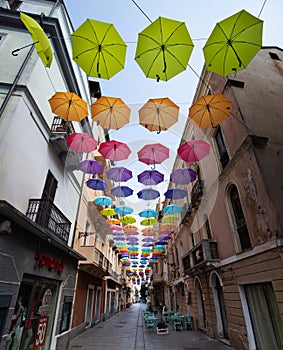 Iglesias, Italy: Colorful umbrellas hanging over a street in old Iglesias city in a sunny day photo