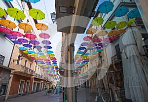 Iglesias, Italy: Colorful umbrellas hanging over a street in old Iglesias city in a sunny day photo