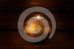 Ignited candle rest on a wooden shelf with copy space for your text