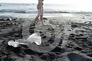 Ignorance woman going to swimming in the coast and garbage in the sand of the beach. Unhygienic sand in the shore. Irresponsible