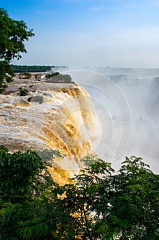 Iguazu waterfalls illuminated in yellow-gold by the low sun