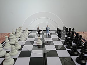 Iillustration for photo War, battle or politic situation concept, 2 standing mini figure, negoitation or debate beyond chess photo