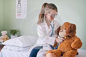 Il make sure your hugs last forever. a little girl pretending to be a doctor while examining her teddybear.