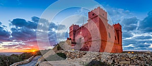 Il-Mellieha, Malta - Tourists watching sunset at St Agatha`s Red Tower with beautiful sky