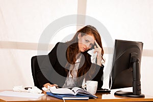 Il woman suffering at work behind the desk in her office