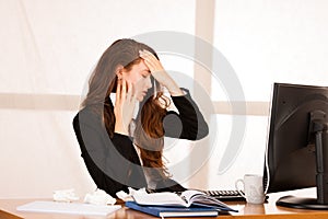 Il woman suffering at work behind the desk in her office