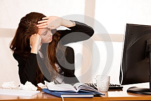 Il woman suffering at work behind the desk in her office