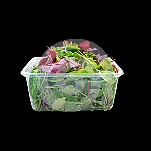 ilettuce leaves in a plastic box isolate. Salad mix in a box.. solated on black