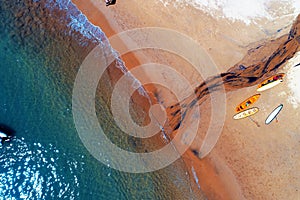 Ilhabela, Brazil: Aerial view of a beautiful beach with red sand and surf board.