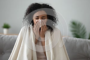 Ill african woman covered with blanket blowing nose got flu