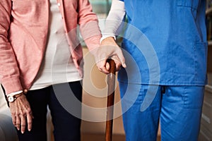 Ill be here every step of the way. Shot of a young nurse assisting a senior woman whos walking with a cane.