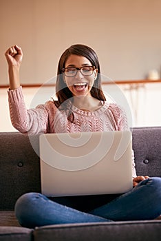 Ill be spending my weekend online. Shot of an attractive young woman using a laptop on the sofa at home and cheering.