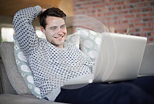 Ill be stunned by technology the day I can download food. a handsome young man relaxing on his sofa while using his