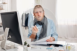 Ill bearded man sneezes, uses handkerchief, feels unwell, has flu. Sick male office worker has fever and tired