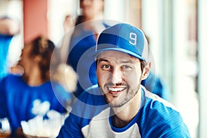 Ill always been true to blue. Portrait of a man watching a sports game with friends at a bar.