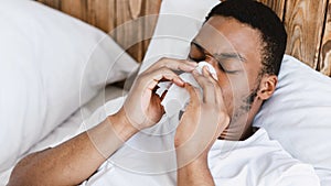 Ill Black Man Blowing Nose In Tissue Lying In Bed