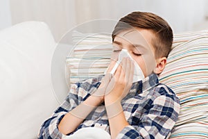 Ill boy lying in bed and blowing his nose at home