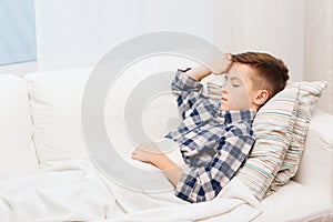 Ill boy lying in bed and suffering from headache