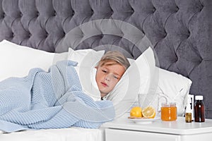 Ill boy suffering from cold in bed and cough remedies