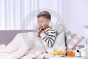 Ill boy suffering from cough on sofa