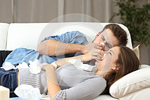 Ill couple sneezing in tissue flu concept