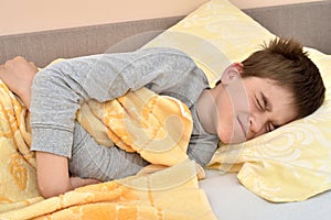 Young boy lying in bed with stomachache photo