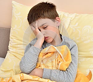 Young boy sitting in bed with headache