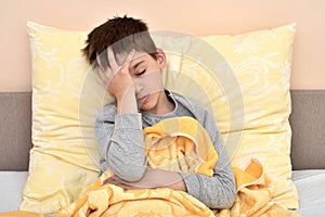 Young boy sitting in bed with headache