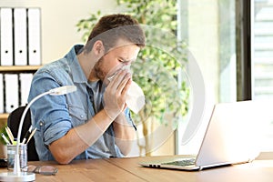 Ill entrepreneur sneezing at office photo