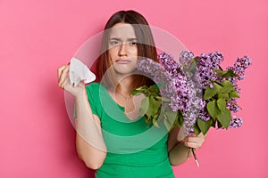 Ill girl with bouquet of lilac flowers, suffers from allergic malaise and rhinitis, seasonal disease, tired of sneezing, allergy