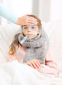 Ill girl child with thermometer and caring mother