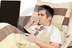 Ill guy with runny nose using laptop on the couch photo