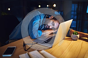Ill just rest my eyes for a little bit. a handsome young businessman asleep at his desk while working late at night in a