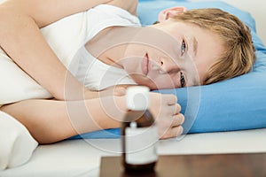 Ill male child laying down next to medicine bottle