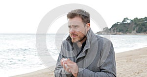 Ill man coughing in a cold day on the beach
